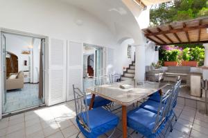a patio with a table and blue chairs at Faraglionensis MonaconeHouse Villa in Capri