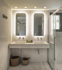 a bathroom with two sinks and two mirrors at Kale Alti residences in Myrina