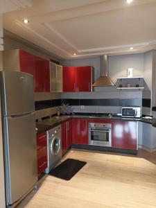 a kitchen with red cabinets and stainless steel appliances at RESIDENCE SOUKHAINA AGADIR MAROC in Agadir