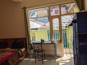 a room with a table and a bed and a window at Golden View B&B in Dharamshala