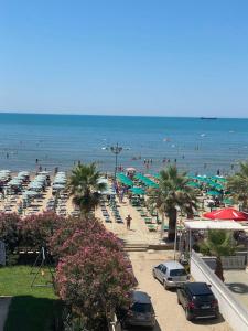 a beach with people and umbrellas and the ocean at Zani’s Apartments in Durrës