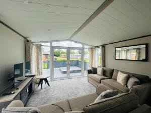 a living room with a couch and a television at Field View Lodge with Hot Tub in York