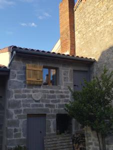 una casa de piedra con una ventana de madera en el lateral. en La Ferme, en Chambles