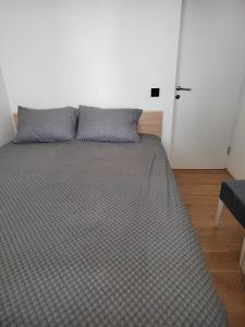 a bed with two pillows on it in a bedroom at Apartman Max in Modriča