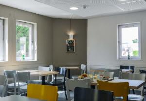 uma sala de jantar com mesas, cadeiras e janelas em B&B HOTEL Metz Jouy Aux Arches em Jouy-aux-Arches