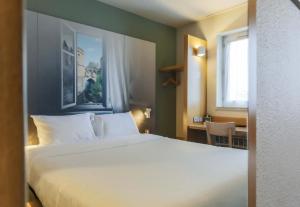 a bedroom with a large white bed and a desk at B&B HOTEL Metz Jouy Aux Arches in Jouy-aux-Arches