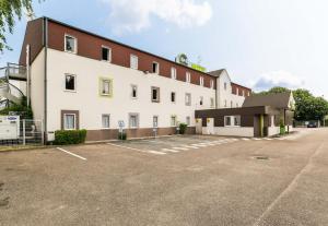 een groot wit gebouw met een parkeerplaats bij B&B HOTEL Metz Jouy Aux Arches in Jouy-aux-Arches