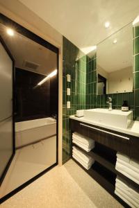 La salle de bains est pourvue d'une baignoire, d'un lavabo et d'un miroir. dans l'établissement FAV LUX Hida Takayama, à Takayama