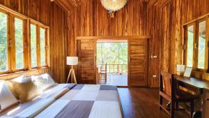 a bedroom with a bed and a desk and windows at Baan Bhuwann Forest Chalet in Koh Phangan