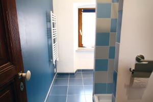 a bathroom with a blue tile floor and a door at LA MAISONNETTE DU POTIER in Caunes-Minervois