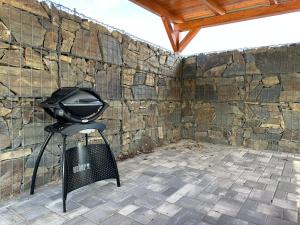 a grill on a stand in front of a stone wall at Apartmány Lošov in Olomouc