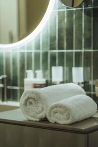 duas toalhas enroladas sentadas numa mesa na casa de banho em Arthotel Lasserhaus em Brixen