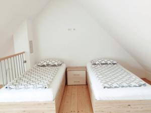 two beds in a room with white walls and wooden floors at Apartments Wallas in Bovec