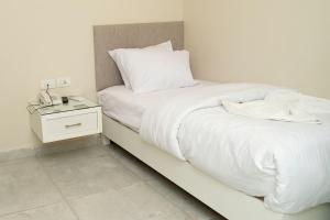 1 dormitorio con 1 cama con sábanas blancas y mesita de noche en Dream House en 6th Of October