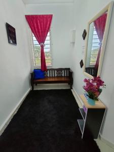 um quarto com um banco e uma janela com uma cortina vermelha em HOMESTAY HAIKALHAIDAR em Rantau Panjang