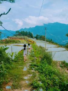 duas crianças a caminhar por uma estrada de terra ao lado de um campo em Lagom Su Phi Retreat em Hoàng Su Phì