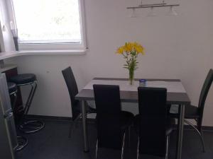 a dining room table with chairs and a vase of flowers on it at #1 Ferienwohnung Hochparterre in Friedrichshafen