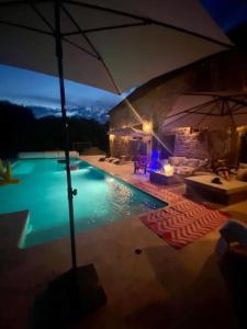a swimming pool at night with an umbrella at L'ancienne Epicerie de POIL in Poil