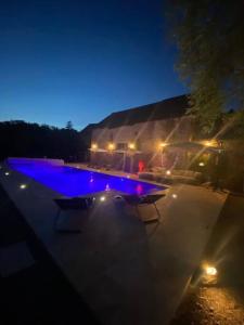 a swimming pool at night with lights on it at L'ancienne Epicerie de POIL in Poil