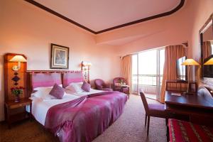 Cette chambre comprend un grand lit et un bureau. dans l'établissement Es Saadi Marrakech Resort - Hotel, à Marrakech