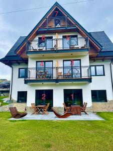 a large house with chairs and tables in front of it at Apartamenty Górajski Spa in Kościelisko