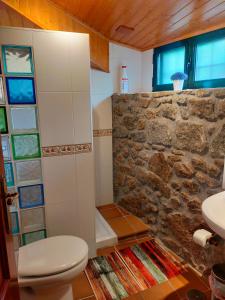 ein Bad mit einem WC und einer Steinmauer in der Unterkunft Senda Verde do Salnés in Portas