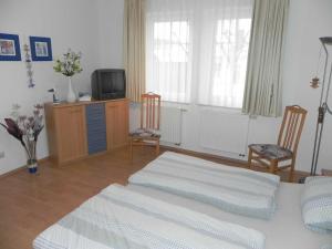 アールベックにあるFEWO am Wilhelmsberg EG01のベッドルーム1室(ベッド1台、椅子2脚、テレビ付)