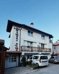 a white car parked in front of a building at Zasheva Kushta Guesthouse in Bansko