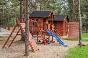 un parque infantil con una casa de madera y un tobogán en W Kaszubskim Lesie Borsk, en Borsk
