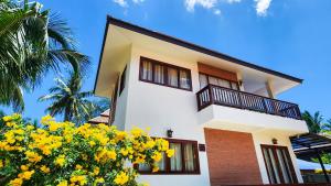 a house with yellow flowers in front of it at Baan Bhuwann Holiday Apartment in Chaloklum