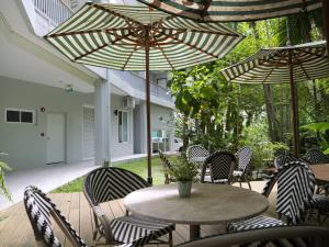 a patio with a table and chairs with umbrellas at Karon beach apartment & sea view pool in Ban Karon