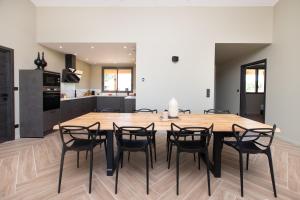 a kitchen and dining room with a wooden table and chairs at La Villa face au Lac in Saramon