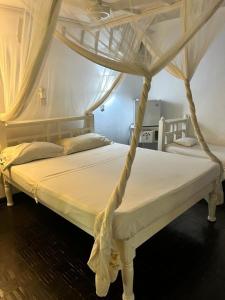 Gemütliches Ferienhaus am weißen Sandstrand في ماليندي: غرفة نوم بسرير أبيض مع مظلة