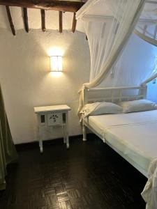 1 dormitorio con 1 cama y 1 mesa con lámpara en Gemütliches Ferienhaus am weißen Sandstrand, en Malindi