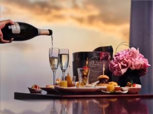 a person pouring champagne into glasses on a table with food at China World Summit Wing, Beijing in Beijing