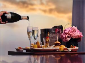 a person pouring champagne into glasses on a table with food at China World Summit Wing, Beijing, A Shangri-La Hotel in Beijing +208 photos
