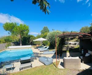 a swimming pool with lounge chairs and an umbrella at L'Angélus in Genay