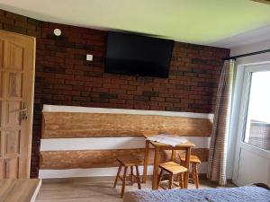Pokoje Goscinne u Naglaka Willa Zab في زومب: تلفزيون على جدار من الطوب مع طاولة وكراسي