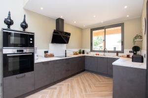 a large kitchen with black cabinets and a large appliance at La Villa face au Lac in Saramon