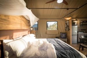 a bedroom with a large bed and a kitchen at Nkuhlu Tented Camp in Skukuza +63 photos