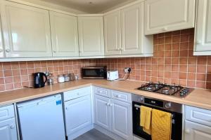 a kitchen with white cabinets and a stove top oven at Large Duplex in Bermondsey in London