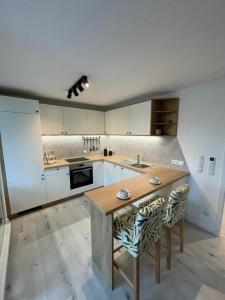a kitchen with white cabinets and a wooden table at xiApartment in Höchst