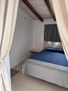a bedroom with a bed with blue sheets and a curtain at Wave Maze in Vila do Maio