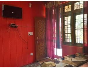 una camera da letto con pareti rosse e una porta con televisore di Safaya Paying Guest House and Home Stay, Patnitop a Patnitop