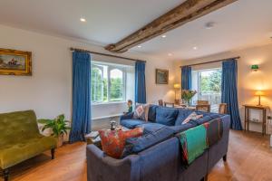 a living room with a blue couch and windows at Lower Lodge Gatehouse at Kentchurch 