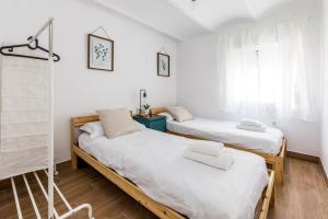 2 camas en una habitación con paredes blancas en Apartamento en CENTRO CIUDAD, en El Puerto de Santa María