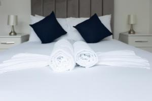 een wit bed met drie opgerolde handdoeken erop bij Imperial liverpool street apartments in Londen