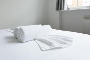 un rollo de papel higiénico blanco sobre una cama en Imperial liverpool street apartments, en Londres