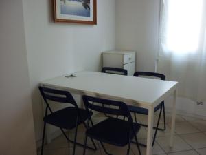 ボローニャにあるLa Mansardaの白いテーブルと椅子4脚が備わる客室です。