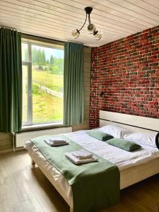 1 dormitorio con 1 cama grande y pared de ladrillo en Friends house bukovel, en Bukovel